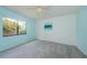 Inviting bedroom with soft gray carpet, bright blue walls, and a large window overlooking the yard at 2609 Sunnyside Cir, Palm Harbor, FL 34684