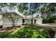Landscaped front yard of single-story home featuring mature trees and attached garage at 2609 Sunnyside Cir, Palm Harbor, FL 34684