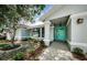 Welcoming entrance with a covered porch, stylish blue door, and tasteful landscaping at 2609 Sunnyside Cir, Palm Harbor, FL 34684