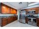 Kitchen featuring stainless steel appliances, brown cabinets, tile floor, and marble countertops at 2609 Sunnyside Cir, Palm Harbor, FL 34684