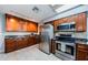 Kitchen featuring stainless appliances, brown cabinets, tile floor, and marble countertops at 2609 Sunnyside Cir, Palm Harbor, FL 34684