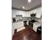 Well-lit kitchen featuring white cabinets, stainless steel appliances, granite countertops, and dark hardwood flooring at 302 W Fern St, Tampa, FL 33604
