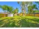 Large backyard with mature trees, a shed and yellow home surrounded by a wood fence at 317 Elizabeth Ave, Clearwater, FL 33759