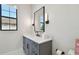 A bright, neutral-toned bathroom with a gray vanity, black hardware, and a framed mirror over a white countertop at 4109 W Inman Ave, Tampa, FL 33609