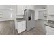 Modern kitchen boasts stainless steel fridge and granite countertops, flowing into the bright living space at 4652 Swallowtail Dr, New Port Richey, FL 34653