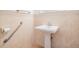 Compact, clean bathroom with a pedestal sink, grab bar, and neutral tiling at 4710 Troydale Rd, Tampa, FL 33615