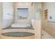 Elegant bathroom featuring a jetted tub, glass shower, and neutral tile throughout at 4710 Troydale Rd, Tampa, FL 33615