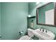 Elegant powder room with pedestal sink, stylish mirror, and soft green walls at 4920 Anniston Cir, Tampa, FL 33647
