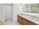 Modern bathroom with dual sinks, wood cabinets, lighted vanity mirror, and tiled floor at 5120 Marina Way # 15005, Tampa, FL 33611