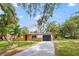 Charming single-story home featuring a gray driveway and tropical landscaping at 5614 Bay Boulevard, Port Richey, FL 34668