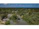 A serene aerial view showcases a neighborhood nestled among lush greenery, with a tranquil pond and distant ocean views at 7332 Janczlik Dr, New Port Richey, FL 34652