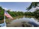 Picture of backyard with an American flag next to a still lake surrounded by lush greenery at 7332 Janczlik Dr, New Port Richey, FL 34652