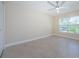Spacious bedroom with a ceiling fan, large window, and neutral wall-to-wall tile flooring at 7332 Janczlik Dr, New Port Richey, FL 34652