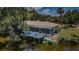 Aerial shot of home featuring a screened in patio, inviting deck with blue railing, and serene waterfront access at 7332 Janczlik Dr, New Port Richey, FL 34652