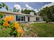 View of the home's white brick exterior, complemented by blue shutters and vibrant flowers at 7332 Janczlik Dr, New Port Richey, FL 34652