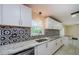 Bright kitchen with stainless steel appliances, granite countertops, white cabinets and a decorative backsplash at 7332 Janczlik Dr, New Port Richey, FL 34652
