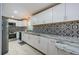 Bright kitchen with white cabinets, granite countertops, decorative black and white backsplash, and stainless appliances at 7332 Janczlik Dr, New Port Richey, FL 34652