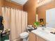Cozy bathroom with a shower featuring a beige curtain, and a wooden vanity cabinet at 7606 Berna Ln, Land O Lakes, FL 34637