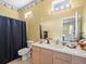 Bathroom with a double sink vanity, toilet, and shower behind a blue curtain at 7606 Berna Ln, Land O Lakes, FL 34637