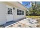 Exterior view showcasing the home's back door, a patio, and a well-manicured lawn at 7704 Tanglewood Ln, Tampa, FL 33615