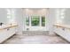 Luxurious bathroom featuring large tub, dual vanities, columns, and a picture window at 7803 Mathern Ct, Lakewood Ranch, FL 34202