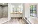 Bright bathroom featuring a double sink vanity, a soaking tub and a glass enclosed shower at 7803 Mathern Ct, Lakewood Ranch, FL 34202