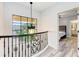 Hallway with wood floors, large window, and decorative wrought iron railing overlooking a bedroom at 7803 Mathern Ct, Lakewood Ranch, FL 34202