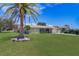 Well-maintained single-story home featuring a lush green lawn and a large palm tree in the front yard at 8289 136Th St, Seminole, FL 33776