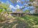 Expansive backyard with a screened porch, lush lawn, and mature trees create a private outdoor space at 852 Village Way, Palm Harbor, FL 34683