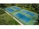 Aerial view of tennis courts surrounded by lush greenery offers ample space for recreation at 852 Village Way, Palm Harbor, FL 34683