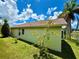 Backyard view of the house, showcasing the lawn and simple landscaping near the waterside at 9614 Long Meadow Dr, Tampa, FL 33615