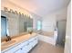 Bathroom featuring double sinks, large mirror, separate shower, and tub at 9614 Long Meadow Dr, Tampa, FL 33615