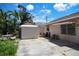 Cozy backyard featuring a shed, table, and partial view of a peach house under a sunny sky at 100 94Th Ave, Treasure Island, FL 33706