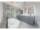 Bright bathroom features a modern soaking tub, walk-in shower, and double vanity with sleek fixtures at 11313 Knights Griffin Rd, Thonotosassa, FL 33592