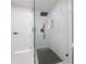 Modern bathroom shower with glass doors, black hardware, mosaic tile floor and white marble walls at 11313 Knights Griffin Rd, Thonotosassa, FL 33592