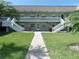 Exterior shot of a light-green building with symmetrically placed stairs and beautiful green lawns at 1250 S Pinellas Ave # 1013, Tarpon Springs, FL 34689
