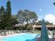 Community pool surrounded by mature trees, lounge chairs, and well-maintained landscaping at 1250 S Pinellas Ave # 1013, Tarpon Springs, FL 34689