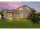 Lush backyard at dusk with the home's rear facade, a covered patio, and ample space for entertaining at 12801 Stanwyck Cir, Tampa, FL 33626