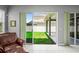 A view of the backyard with green grass, privacy fence and covered patio seen through sliding glass doors at 12801 Stanwyck Cir, Tampa, FL 33626