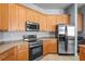 Kitchen with wooden cabinets, stainless steel appliances, and tiled flooring, ready for culinary adventures at 12801 Stanwyck Cir, Tampa, FL 33626