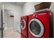 Modern laundry room with red washer and dryer, white cabinets, and tile flooring at 12801 Stanwyck Cir, Tampa, FL 33626