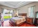 Main bedroom features a tray ceiling, wood floors, ensuite and sliding door access to back yard at 12801 Stanwyck Cir, Tampa, FL 33626