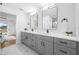 Gray vanity in updated bathroom with dual sinks, modern fixtures, mirrors, and marble-patterned floors at 12879 112Th St, Largo, FL 33778