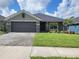 Charming single-story home featuring a well-manicured lawn and a two-car garage with a brick-paved driveway at 13334 Ogden Glade Rd, Dade City, FL 33525