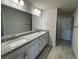 Bathroom featuring double sinks, granite countertops, and modern wood-look tile flooring at 13374 Ogden Glade Rd, Dade City, FL 33525