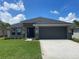 Charming single-story home featuring a manicured lawn, stone accents, and an attached two-car garage at 13374 Ogden Glade Rd, Dade City, FL 33525