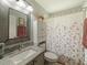 Bright bathroom showcases a granite countertop vanity, matching mirror, linen closet, and shower with floral curtain at 18930 Wood Sage Dr, Tampa, FL 33647