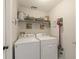 Well-organized laundry room with washer, dryer, shelving, and decor at 18930 Wood Sage Dr, Tampa, FL 33647