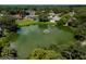 Aerial view of home, lush landscaping, a lake with fountain, and neighborhood at 2406 Dana Dr, Safety Harbor, FL 34695