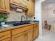 Classic kitchen with wood cabinets, black sink, and a decorative tile backsplash at 2442 Enterprise Rd # 6, Clearwater, FL 33763